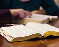 Two people studying open Bibles—hands only